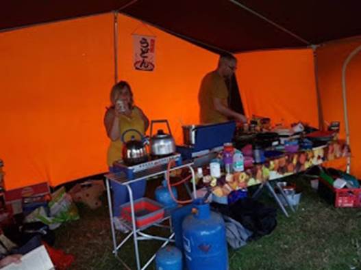 A person and person cooking in a tent

Description automatically generated